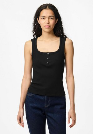Débardeur noir à côtes avec encolure carrée, comportant trois boutons-pression et des bretelles larges. Associé à un jean en denim bleu foncé.