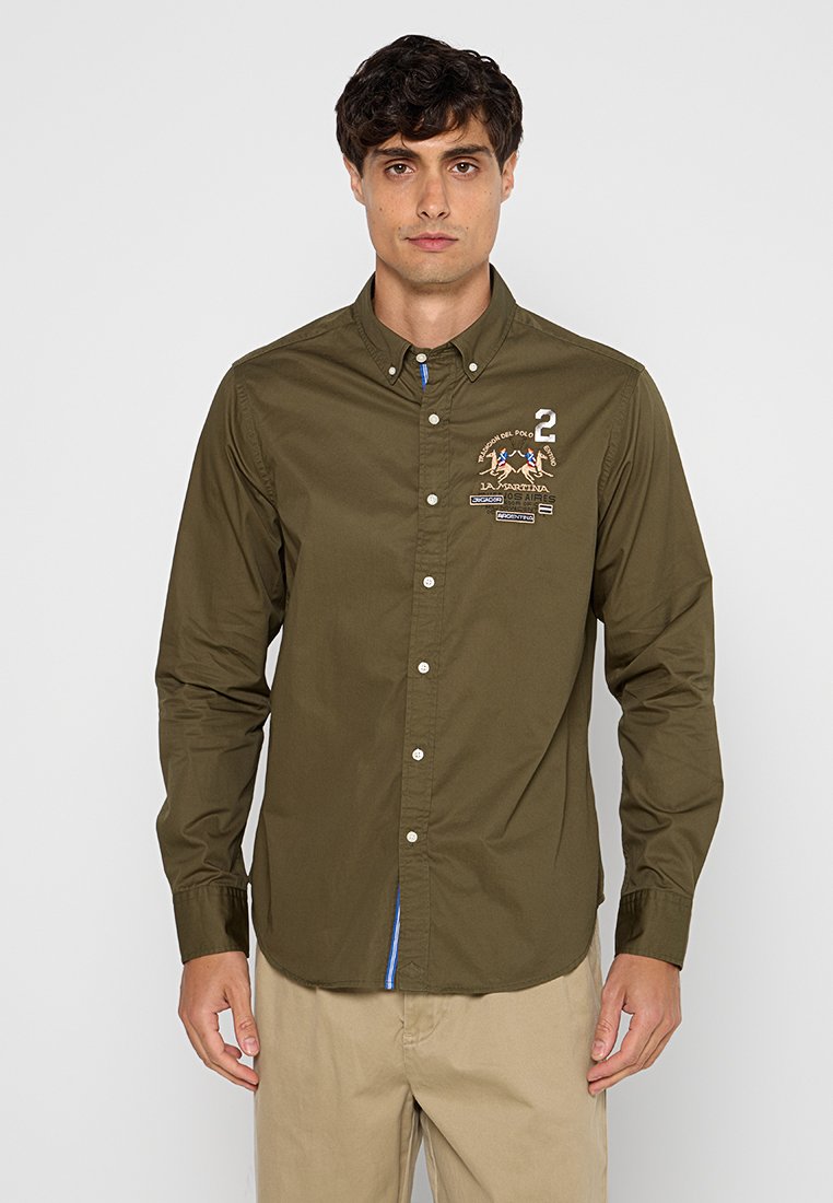 Camicia button-up verde oliva in cotone con un design a polo cucito, colletto e un accento blu sotto l'orlo. Presenta bottoni bianchi.