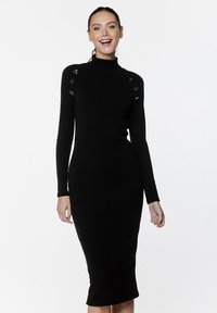 Czarna dzianinowa sukienka z prążkowanej tkaniny, z długimi rękawami, wysokim kołnierzem i srebrnymi guzikami na ramionach. Dopasowany krój do długości w połowie łydki.