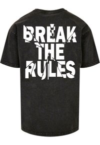 Zwarte katoenen t-shirt met korte mouwen, voorzien van grote witte tekst op de achterkant met de tekst "BREAK THE RULES", in een versleten uitstraling.