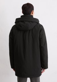 Schwarze, gepolsterte Jacke mit hohem Kragen und Kapuze, langen Ärmeln und einem geraden Schnitt, der bis zur Mitte des Oberschenkels reicht. Glatte Textur.