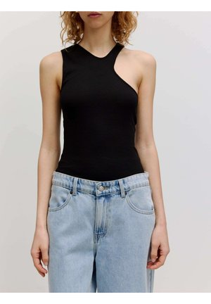 Zwarte, aansluitende tanktop met een asymmetrische halslijn, gemaakt van rekbaar materiaal, gecombineerd met lichtblauwe high-waisted jeans.