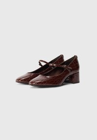 Brown croc-embossed leather Mary Jane shoes with a low block heel and adjustable strap on a white background.