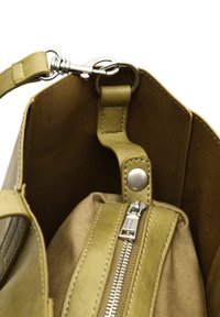 Olive zelená kožená kabelka zvnútra s béžovým látkovým podšívaním, s vreckom na zips a striebornými kovovými akcentmi.