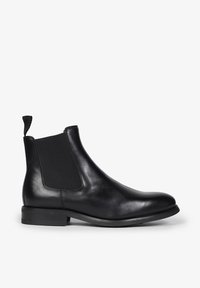 Sorte læder Chelsea støvle med elastiske sidelapper, rund tå, optrækningstap og en lav stablet hæl. Glat tekstur med minimalistisk design.