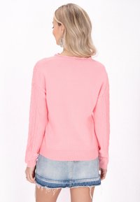 Maglione rosa con maniche a coste a trama cable-knit e orlo a coste, abbinato a una mini gonna in denim blu. Il retro presenta un design semplice.