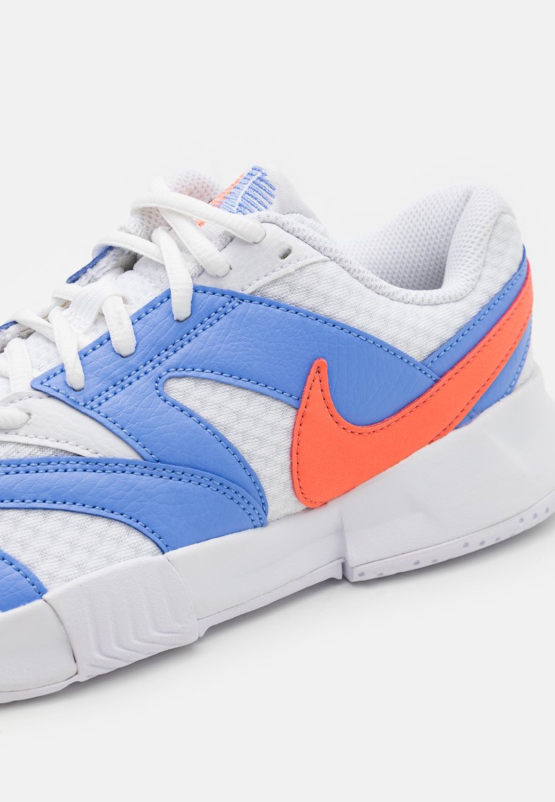 Zapatilla blanca con acentos en azul y naranja, parte superior sintética texturizada, forro de malla y suela de goma plana.