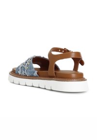 Brown leather sandals with a blue distressed denim upper, white rubber sole, and decorative studs. Features adjustable ankle strap.