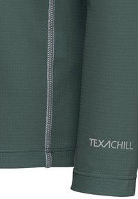 Haut en tissu vert foncé à manches longues avec une surface texturée, des coutures contrastées en gris clair et "TEXACHILL" imprimé en blanc à l'ourlet.