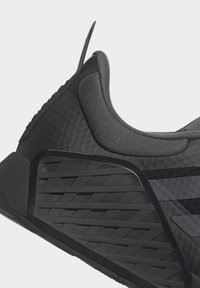 Zapato deportivo negro con una superficie texturizada, cuello acolchado y una suela con patrón y acentos de goma, todo con un diseño aerodinámico.