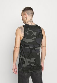 Pánska bezrukávová tank top s maskáčovým vzorom v odtieňoch tmavozelenej a sivej, so zaobleným výstrihom a voľným strihom, vyrobený z jemnej bavlnenej tkaniny.