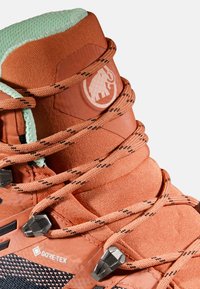 Oranje wandelschoen met textiel, vetersysteem, lichtgroene kraag en zwarte hardware. Beschikt over een GORE-TEX-logo aan de zijkant.