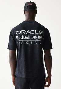Μαύρο κοντομάνικο μπλουζάκι με μαρμάρινη υφή. Δείχνει το λευκό λογότυπο "Oracle Red Bull Racing" στην πλάτη. Κατασκευασμένο από βαμβάκι.