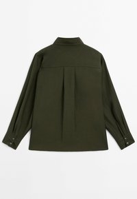 Chemise à manches longues vert foncé avec pli dans le dos, poignets boutonnés et col structuré, posée à plat sur fond blanc.