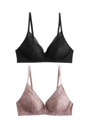 Femme portant un bralette en dentelle noire et un délicat collier chaîne avec un pendentif rond, de profil sur un fond clair.