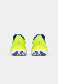 Running shoes with a bright yellow mesh upper, blue accents, and white sole. Heel features reflective detail and textured grip.