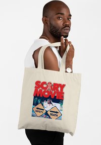 Bolsa tote de lienzo beige con impresión gráfica que presenta el texto "PELICULA DE MIEDO" y dos letreros etiquetados como "SEGURIDAD" y "MUERTE". Mangos resistentes para transportar.