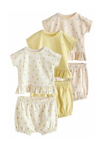 Set van vier lichte katoenen outfits in pastelgeel en crème, met ruches aan de onderkant en speelse patronen van citroenen en kersen.