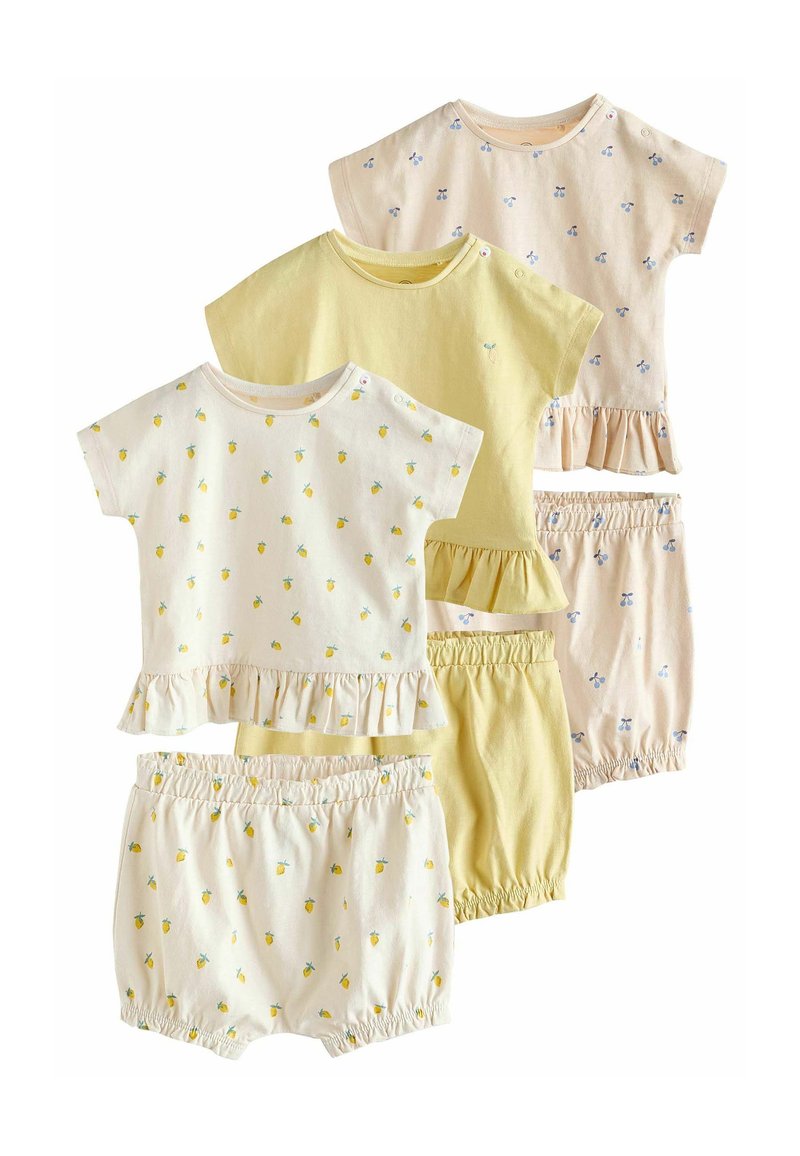 Set van vier lichte katoenen outfits in pastelgeel en crème, met ruches aan de onderkant en speelse patronen van citroenen en kersen.
