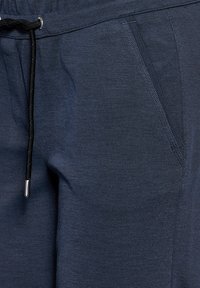 Navyblauwe broek van gestructureerde stof, voorzien van een koordsluiting met zilveren accenten en zijzakken.