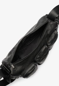 Zwarte leren tas met een gestructureerde afwerking, voorzien van een hoofdcompartiment met ritssluiting en een kleiner zijvak, verstelbare schouderband.