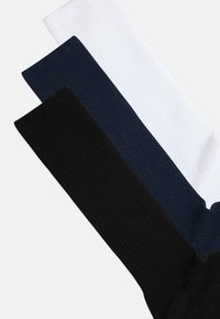 Randiga strumpor i tre färger: svart, marinblå och vit. Varje par har en konsekvent struktur och slät finish.