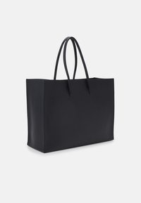 Sac de tote en cuir noir avec une texture lisse, de forme rectangulaire et deux longues anses, sans fermetures ni ornements visibles.