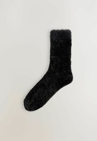Black fluffy sock with a soft, textured body and a furry cuff at the top. It has a rounded toe and a smooth sole.