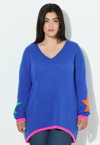 Maglione blu a maglia con scollo a V, caratterizzato da accenti di stelle verdi e arancioni, e orlo e polsini rosa a costine. Maniche lunghe, vestibilità comoda.