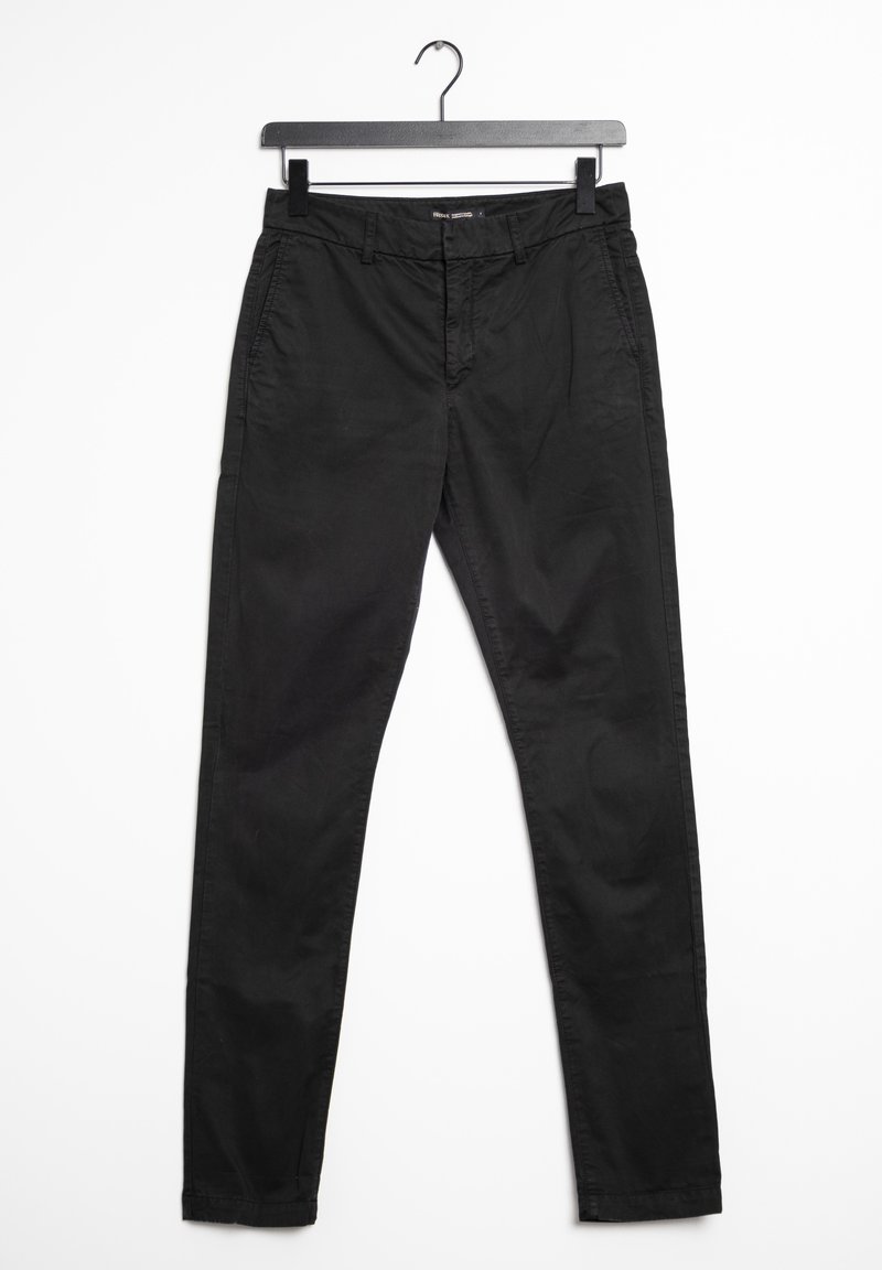 Pantalon slim noir suspendu à un cintre noir sur fond blanc.