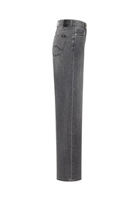 Jean en denim gris à jambe droite vu de côté, avec une poche arrière présentant des surpiqûres discrètes et une étiquette en cuir noir sur la ceinture.