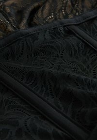 Tela de encaje negro con un patrón floral y una textura fina similar a una red, con acentos negros sólidos a lo largo de los bordes. Apariencia suave y ligera.