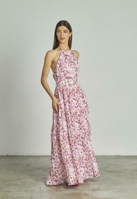 Vestido maxi de tejido ligero que presenta un cuello halter, una cintura ajustada con un cinturón a juego y un patrón de flores en tonos rosa y morado.