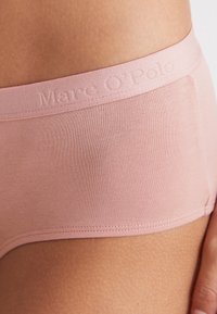 Ljusrosa hipsterunderkläder i mjukt, elastiskt tyg. Har en präglad varumärkeslogotyp på midjebandet och en sömlös design.