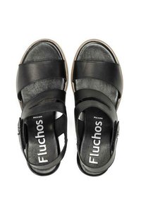 Sandalias de cuero negro con múltiples correas anchas, plantilla acolchada y suela de goma ligeramente elevada con un detalle de hebilla plateada.