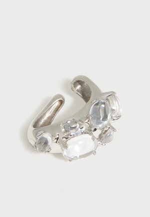 Inel deschis din argint cu mai multe pietre prețioase clare, ovale și rotunde, așezate de-a lungul benzii pe un fundal alb.