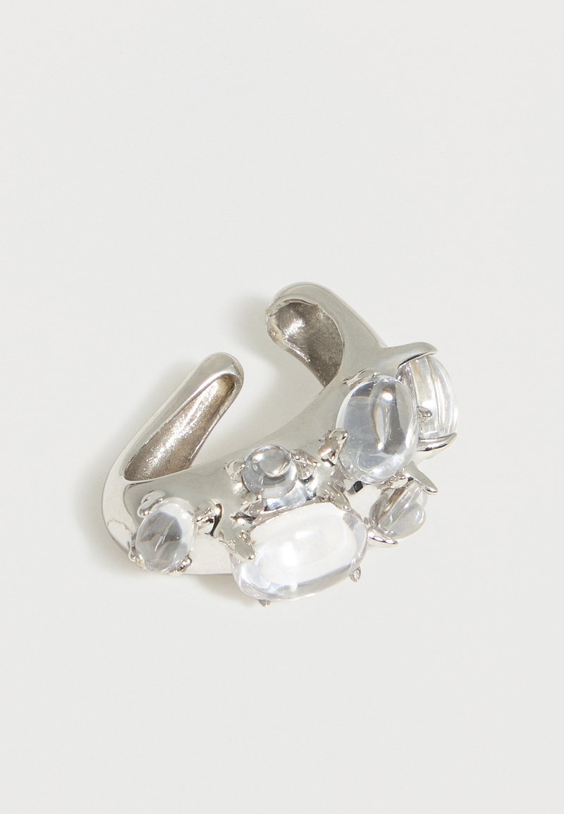 Ασημένιο ανοιχτό δαχτυλίδι με πολλούς διαυγείς οβάλ και στρογγυλούς πολύτιμους λίθους τοποθετημένους κατά μήκος της μπάντας σε λευκό φόντο.