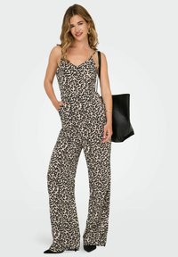 Tuta con stampa leopardata, spalline sottili, gambe larghe, tasche e vestibilità comoda, realizzata in tessuto leggero. Accessorio borsa nera.