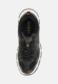 Zwarte sneaker met een gestructureerde bruine en zwarte accent. Heeft een textuur, vetersluiting aan de voorkant en een witte rubberen zool. Gouden logo zichtbaar.