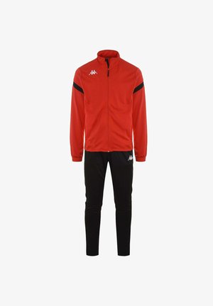 Tuta rossa con giacca zip-up dotata di dettagli neri e colletto alto, abbinata a pantaloni jogger neri a sigaretta. Realizzata in tessuto tecnico sportivo.