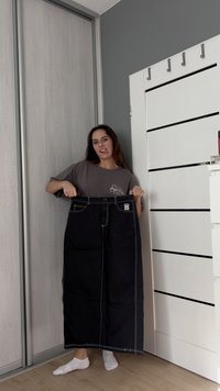 Svart stripete bukser med bred beinvidde, frontlommer og midjebånd. Tøyet har en glatt tekstur. En logo er synlig nær midjebåndet.