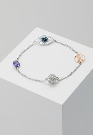 Bracelet délicat en chaîne d'argent avec un pendentif en forme d'œil, une pierre précieuse violette, une sphère incrustée de cristaux et un pendentif rond en or rose avec écriture.