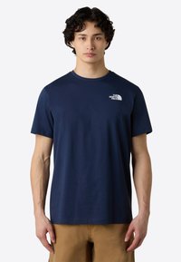 Mørkeblå kortærmet t-shirt lavet af blødt stof, med et lille hvidt logo på brystet og en standard rund halsudskæring.