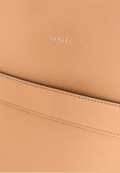 Чанта Lancel Paris в мека бежова текстурирана кожа, с дискретни шевове и релефно лого, с гладък и чист дизайн.