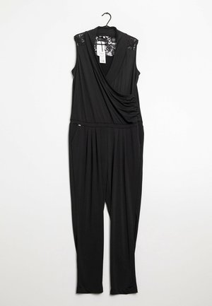 Schwarzer ärmelloser Overall mit Spitzeneinsätzen an den Schultern, drapiertem V-Ausschnitt, plissierten weiten Beinen und Seitentaschen, hängend an einem schwarzen Kleiderbügel.