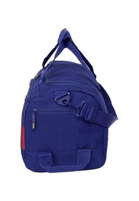 Niebieska torba sportowa z zamykaną boczną kieszenią, regulowanym paskiem na ramię i podwójnymi uchwytami, pokazana z boku na białym tle.
