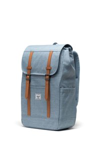 Light blue fabric backpack with brown leather straps and accents, square shape, flap top, front pocket, and padded mesh back.