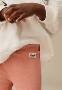 Minni Mus rosa ribbade leggings med etikett, tillsammans med en vit sweatshirt med grafisk design och ribbade muddars.