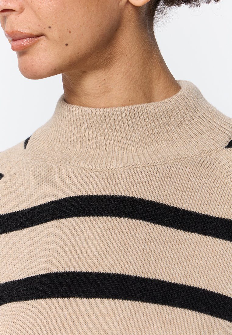 Maglione beige lavorato a maglia con un collo alto a costine; presenta audaci strisce orizzontali nere. Tessuto morbido, design aderente.