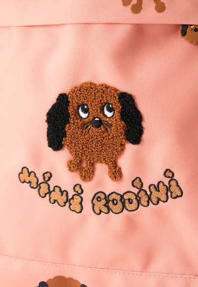 Cão de cartoon bordado em castanho e preto com grandes olhos em tecido rosa, com o texto "Mini Rodini" bordado abaixo.